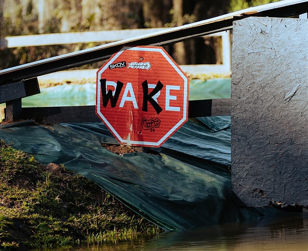 Placa icônica de WAKE com obstáculos desafiadores ao fundo